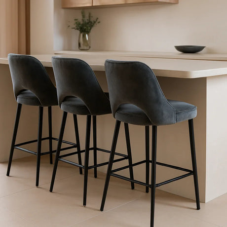 Vier donkergrijze velvet barkrukken aan een moderne keukenbar