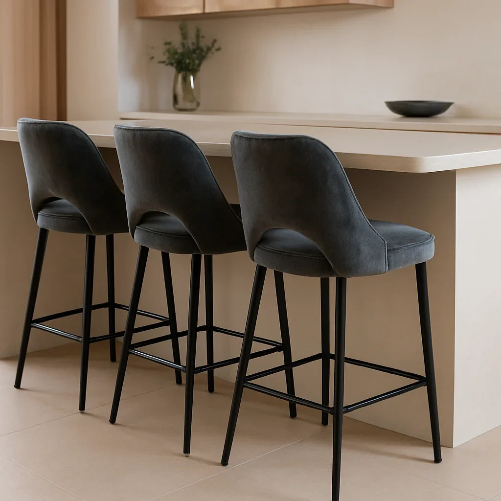 Vier donkergrijze velvet barkrukken aan een moderne keukenbar