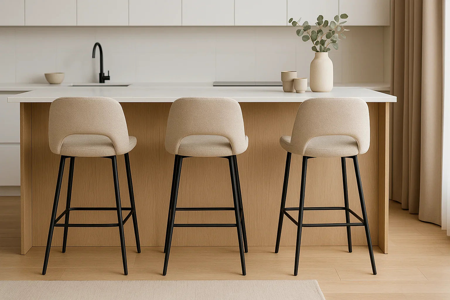 Drie beige barkrukken met zwarte poten aan een licht houten keukeneiland in een moderne minimalistische keuken.
