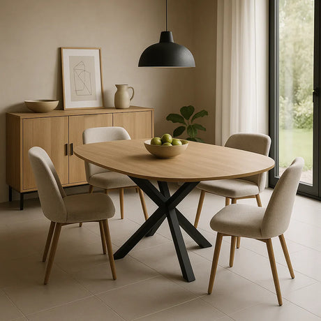 Moderne eetkamertafel van ovaal hout met zwart metalen kruispoot, omringd door beige gestoffeerde stoelen in een lichte eetkamer met veel daglicht.