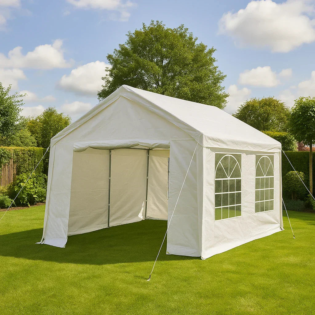 Witte partytent met ramen opgesteld op een groen gazon onder een blauwe lucht met enkele wolken