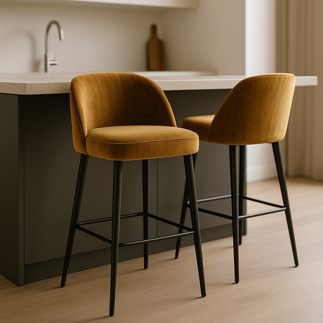 Twee velvet barkrukken met zwarte poten aan een moderne keukenbar met houten vloer en licht interieur