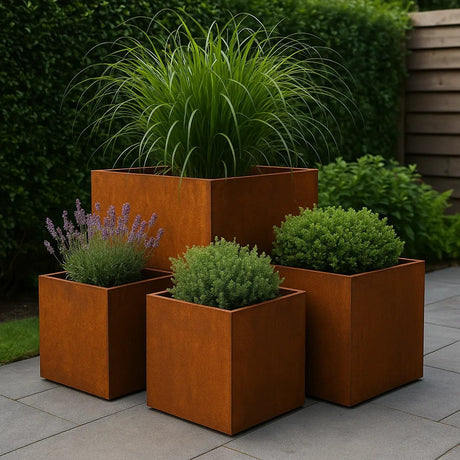 Een grote cortenstalen plantenbak gevuld met siergrassen op een strak terras in een groene tuinomgeving