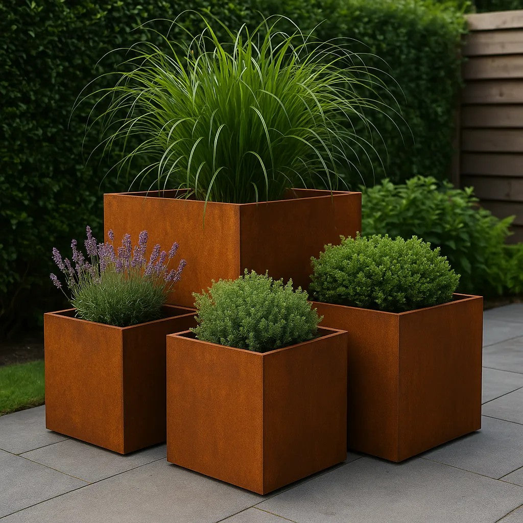 Een grote cortenstalen plantenbak gevuld met siergrassen op een strak terras in een groene tuinomgeving
