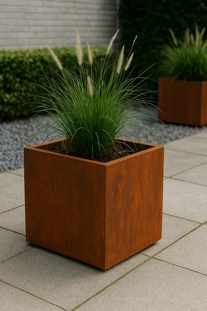 Cortenstaal plantenbak met siergrassen op een betegeld terras