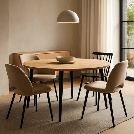 Moderne ronde eetkamertafel van hout met vijf gemixte stoelen in een lichte, minimalistische eetruimte.